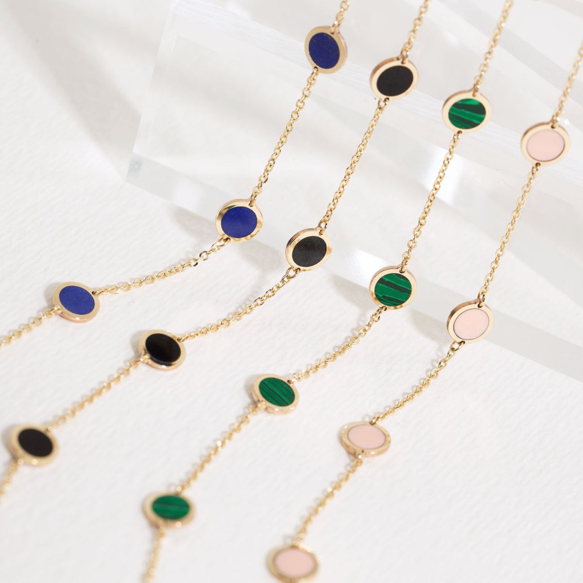 14K gold lapis lazuli station bracelet shown beside black, malachite and pink-disc styles on a white background