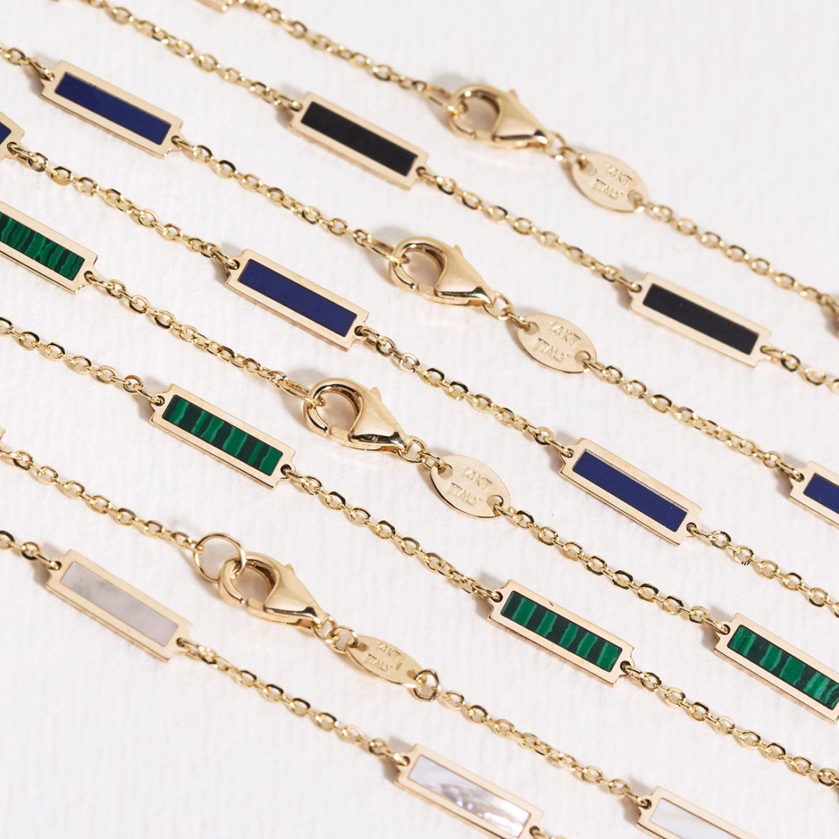 14K gold onyx bar bracelet shown angled with other gemstone bar bracelets and their clasps