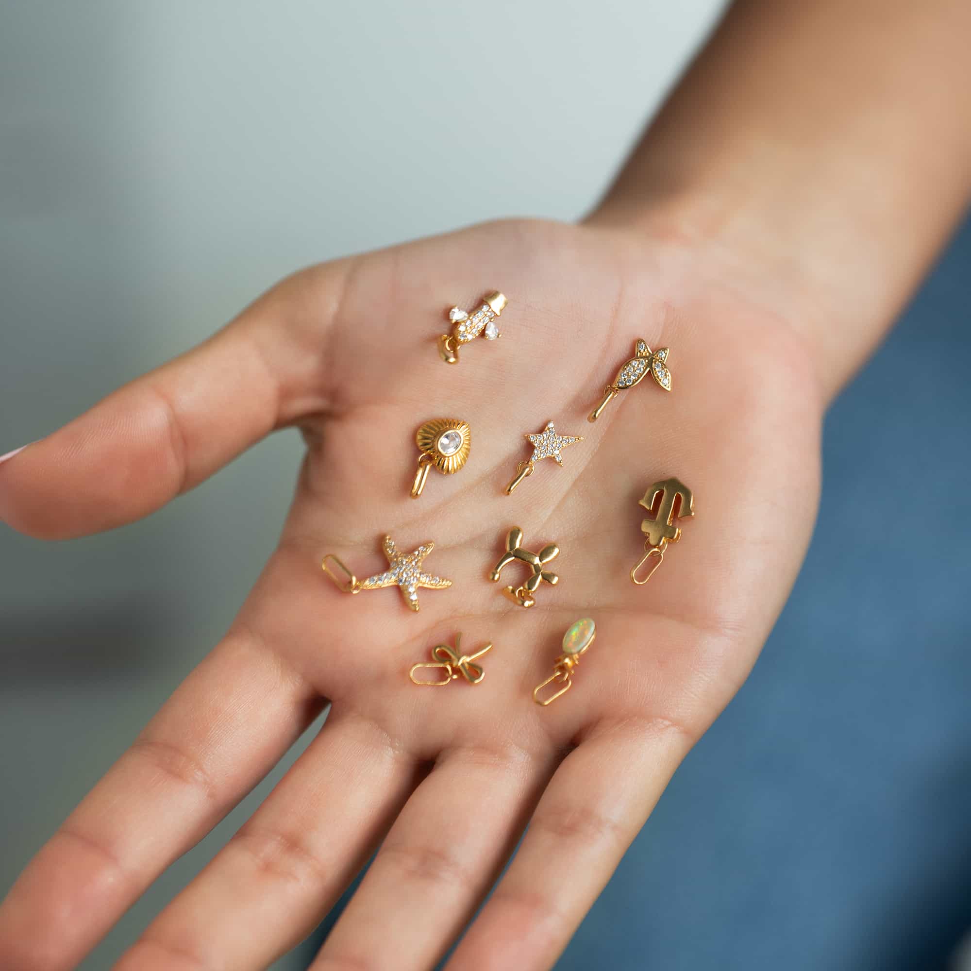 An assortment of small gold stud charms — a star, starfish and clear-stone shapes, held in an open palm