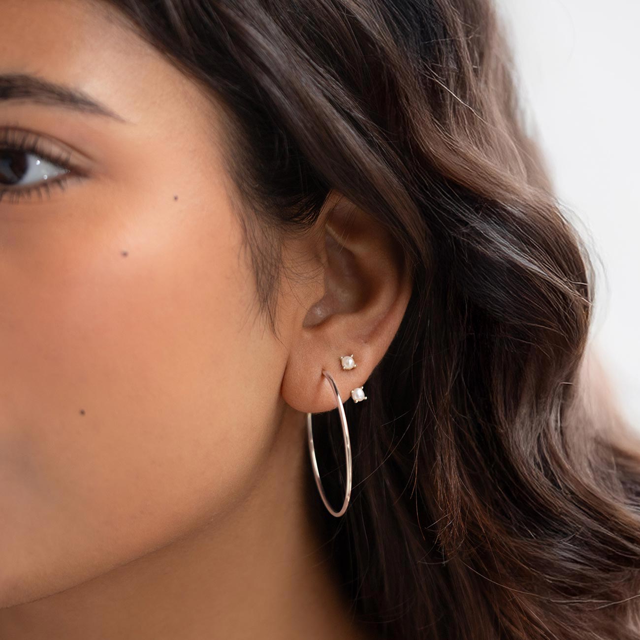 Sterling silver thin midi hoop with small square stone studs, shown on a model's ear
