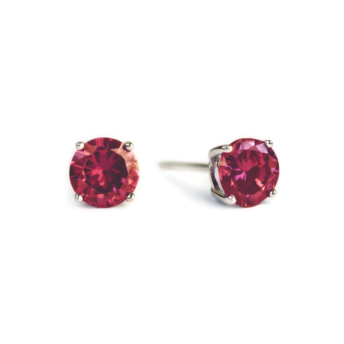 Sterling silver ruby studs with round red stones in four-prong settings, on a white background