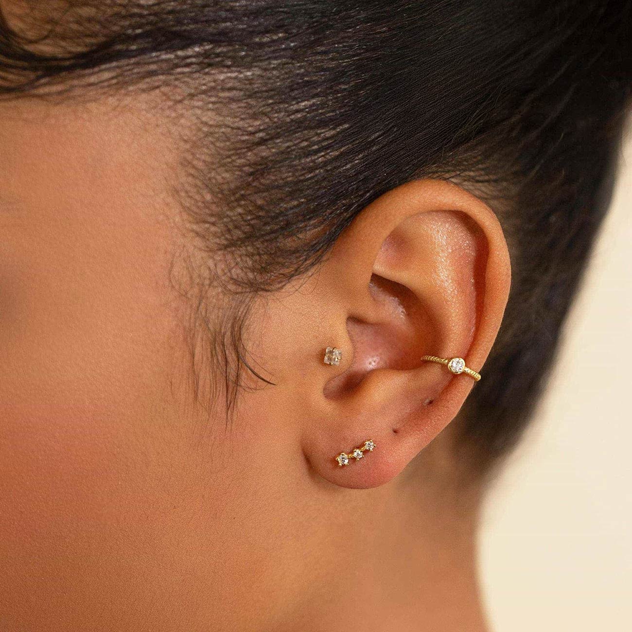 Gold twisted-rope ear cuff with a clear stone, shown on a model's upper ear