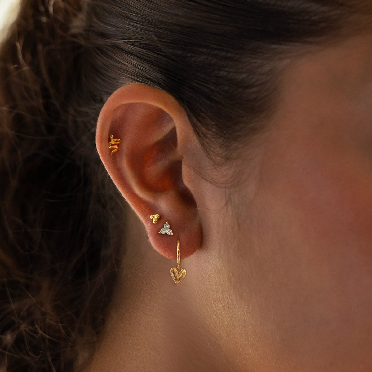 Gold vermeil white zirconia trio flat back stud shown on a model's ear lobe in an ear stack