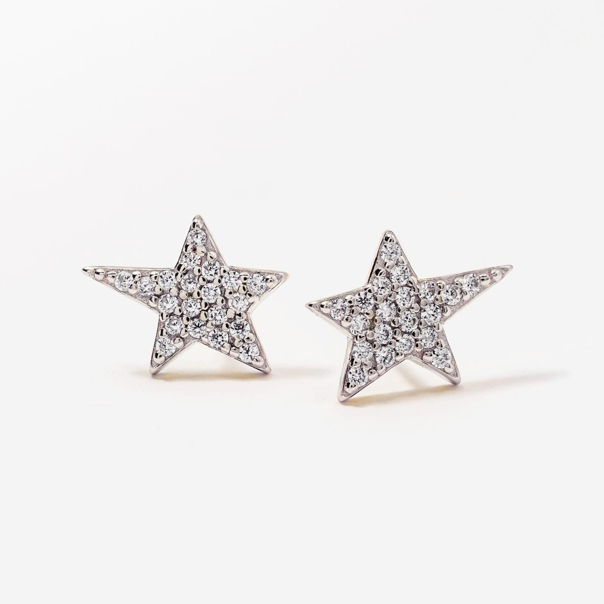 Sterling silver pavé star studs with white zirconia, angled close-up detail on a cream background