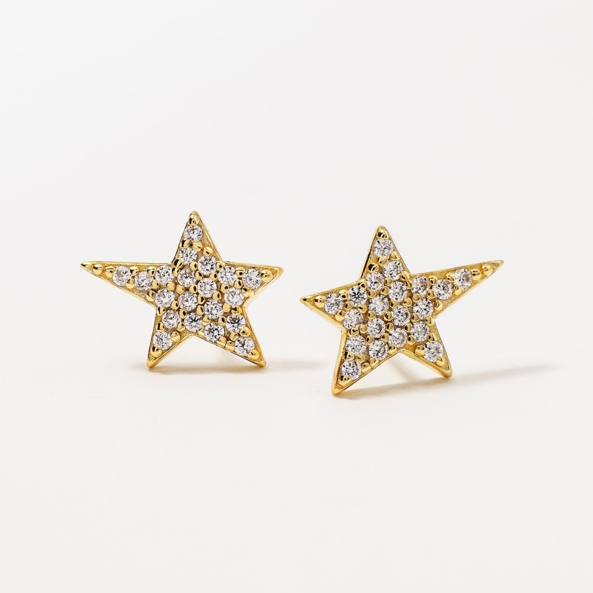 Gold vermeil pavé star studs with white zirconia, angled close-up detail on a cream background