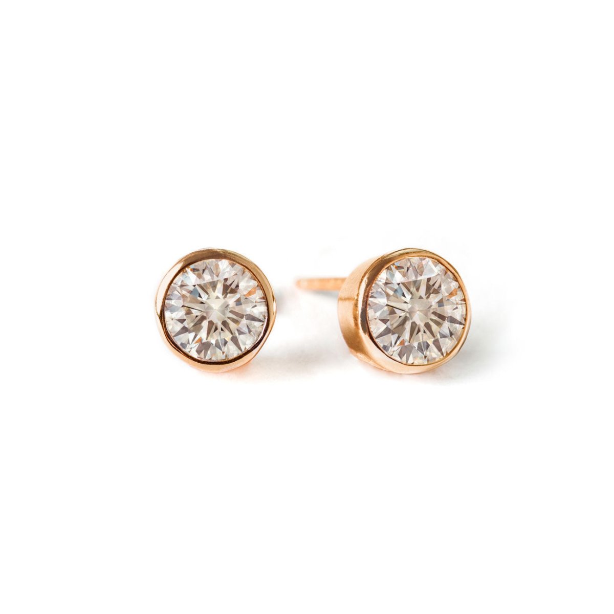 Pair of rose gold vermeil bezel-set white zirconia stud earrings, on a white background