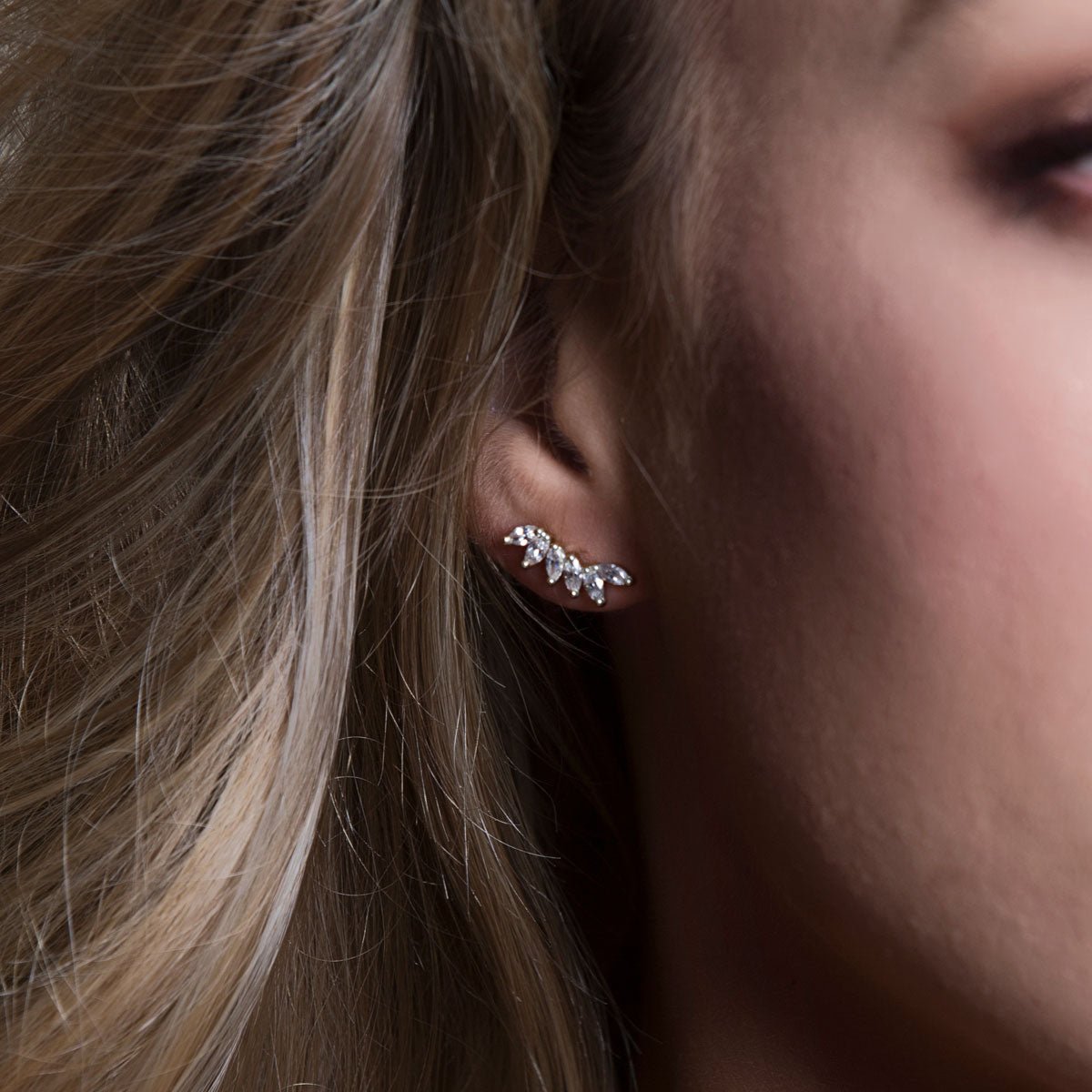 Sterling silver curved climber earring with white zirconia marquise stones, shown on a model's lobe