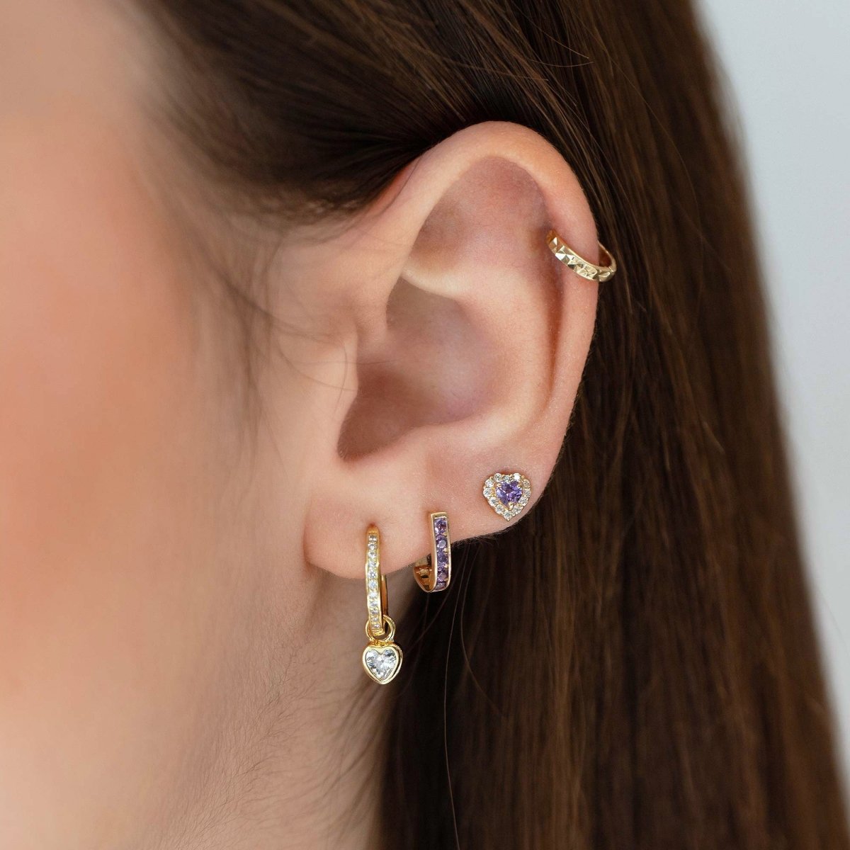 14K gold heart-cut amethyst halo stud shown on a model's earlobe with hoops and an ear cuff
