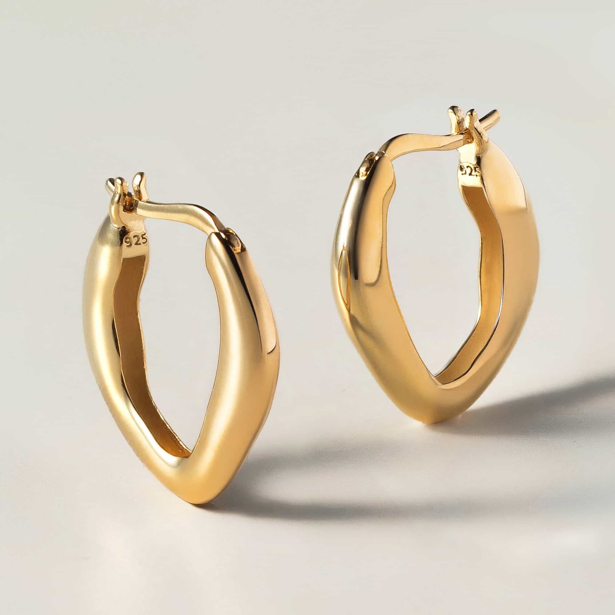 Gold vermeil sculptural mini hoops, angled close-up showing the hinged closure, on a white background