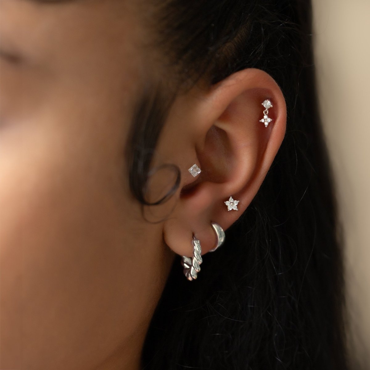 Sterling silver flat back studs with clear white zirconia shown across a model's curated ear stack
