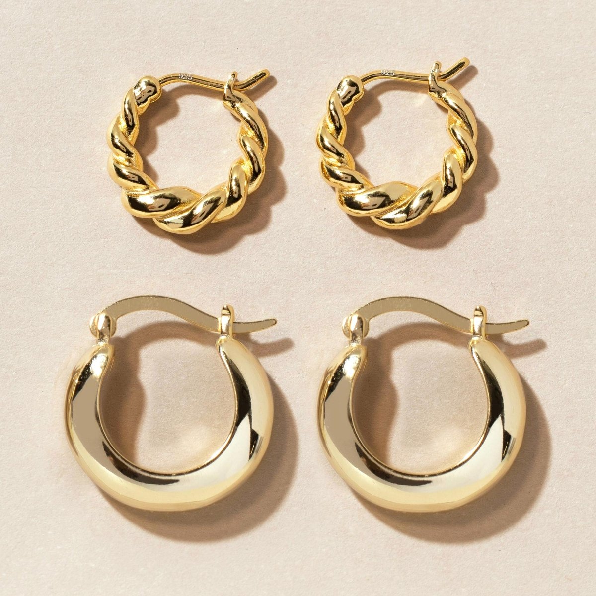 Gold vermeil hoop earrings, a twisted pair and a smooth thick pair, shown on a cream background