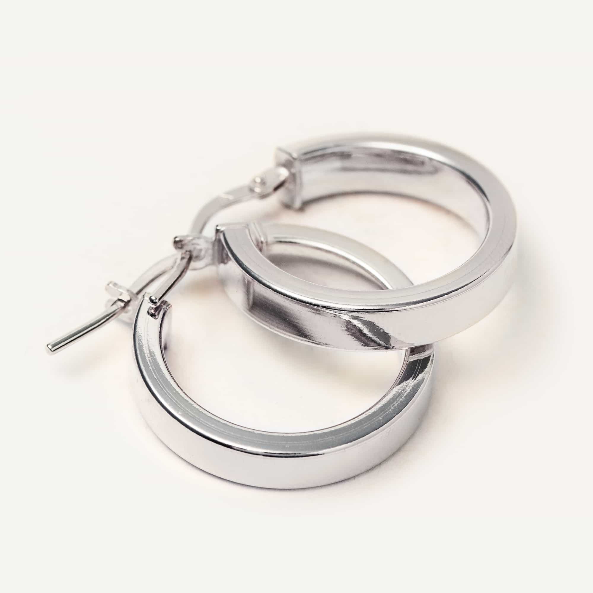 Sterling silver flat block hoop earrings shown lying angled on a white background