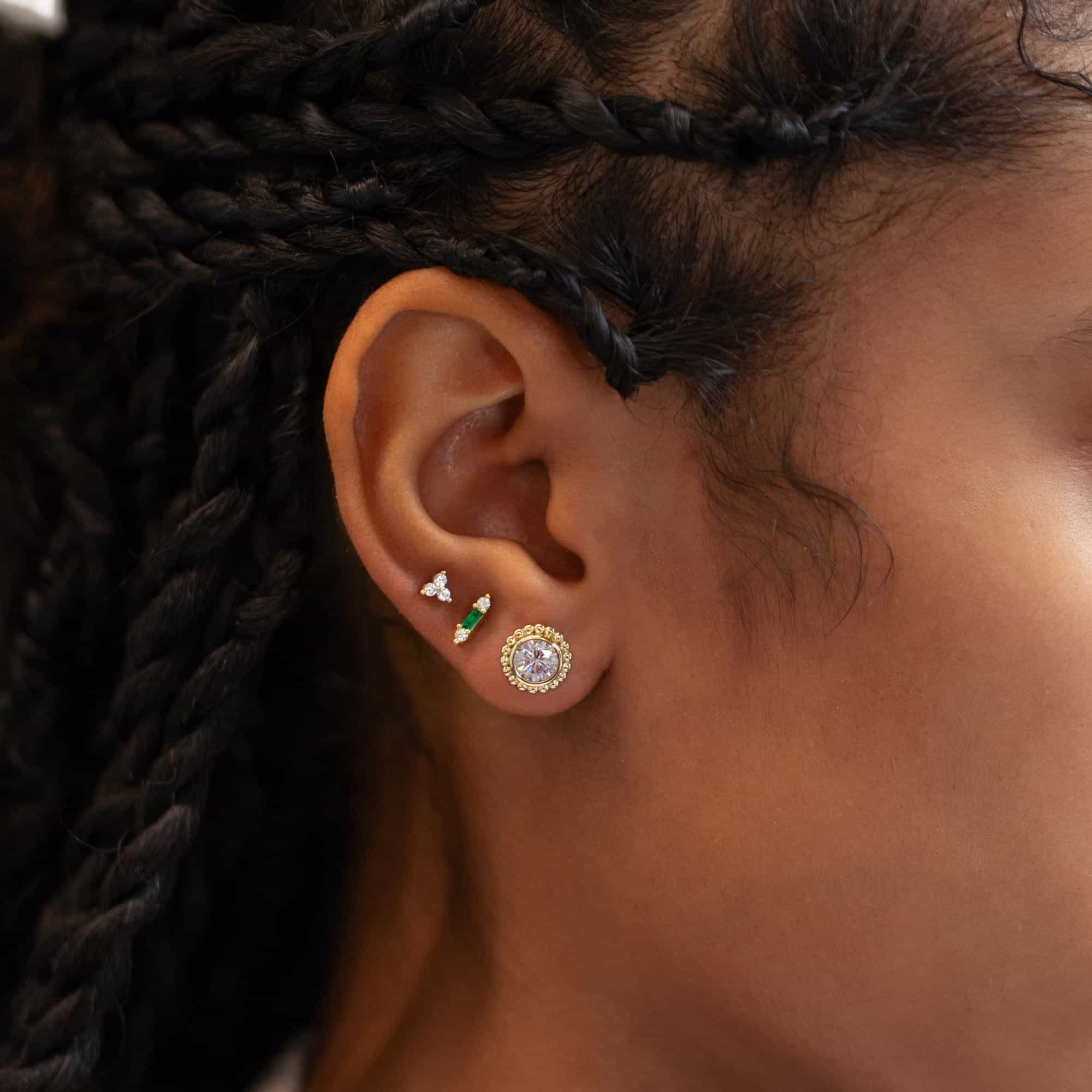 Gold vermeil beaded halo stud with a clear stone shown on a model's lobe in an ear stack