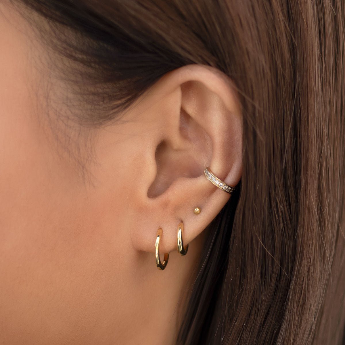 Gold titanium tiny sphere flat back stud shown in a lobe stack with hoops on a model