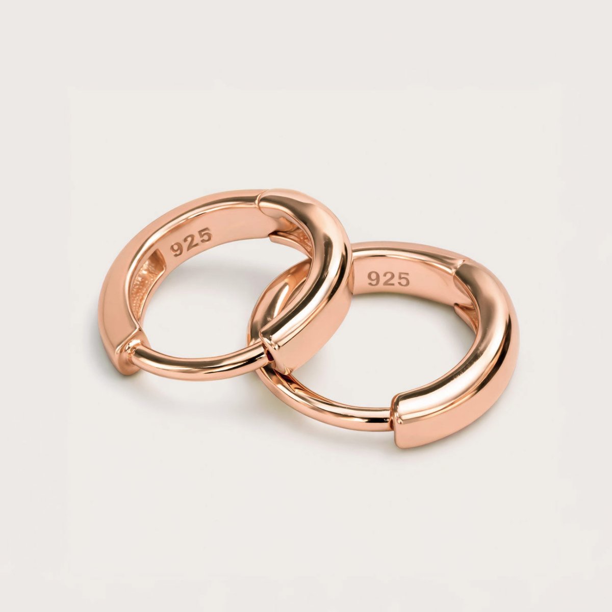 Rose gold vermeil huggie hoops with a thick rounded band, close-up detail on a white background