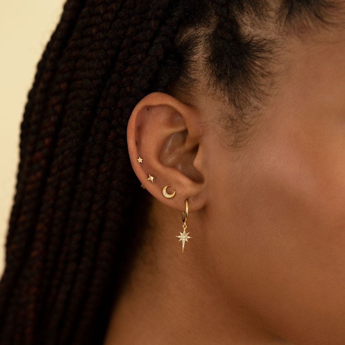 14K gold star and moon studs with a star-charm huggie hoop shown in a styled ear stack
