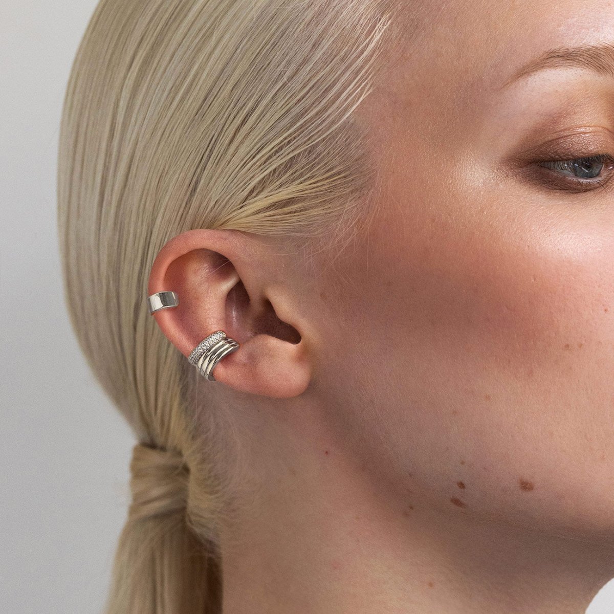 Sterling silver ear cuffs with a pavé clear-stone band, shown on a model's conch and helix