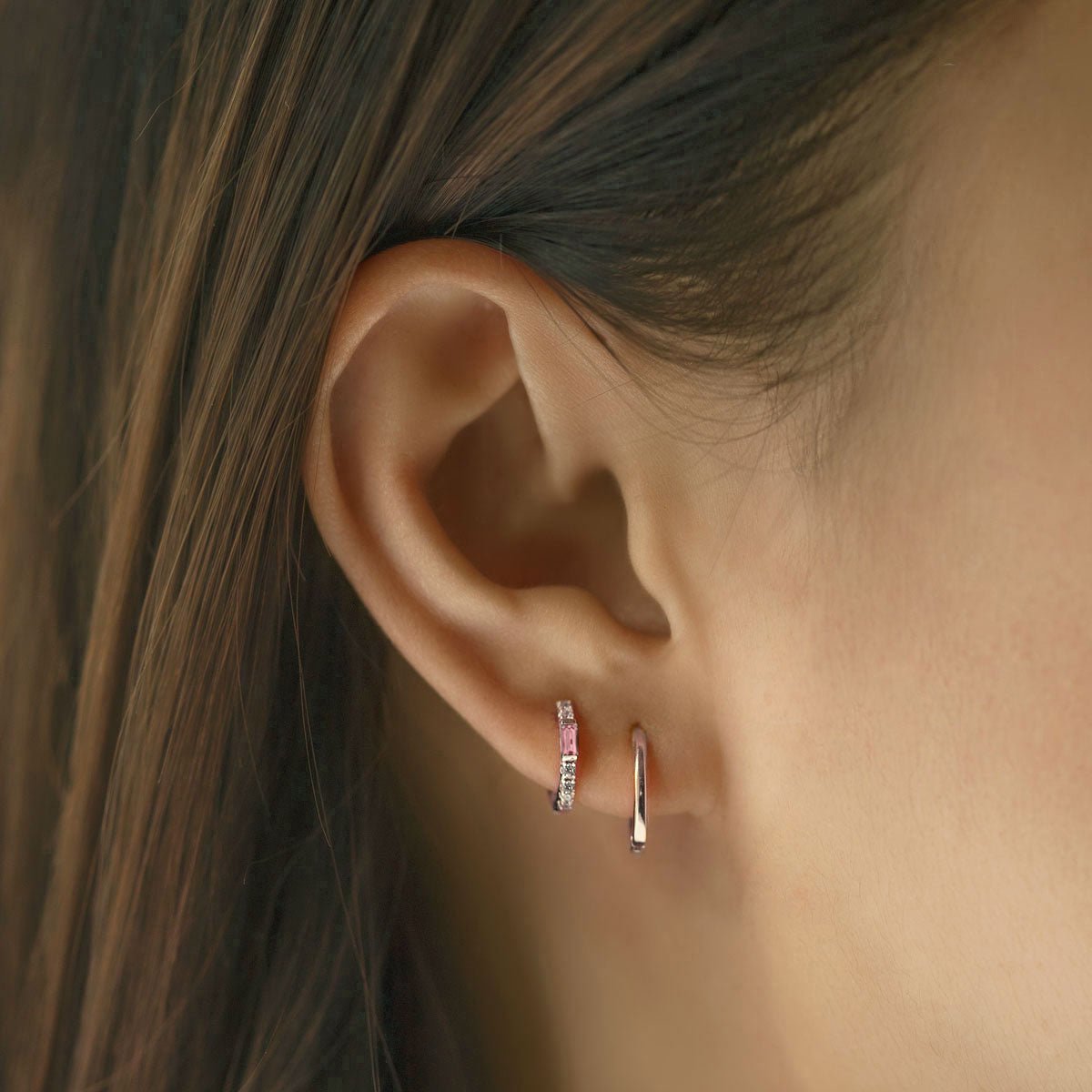 Close-up of woman's ear featuring Sterling Silver Gemstone Baguette Huggie Earrings Pink and silver hoops.