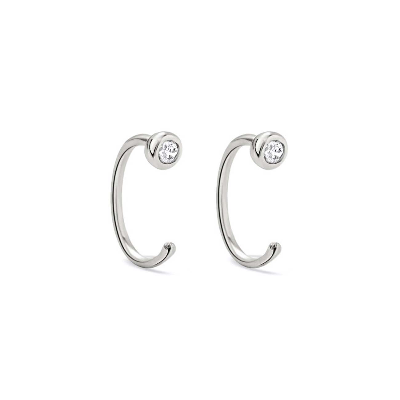 Sterling silver open huggie earrings with bezel-set white zirconia, on a white background