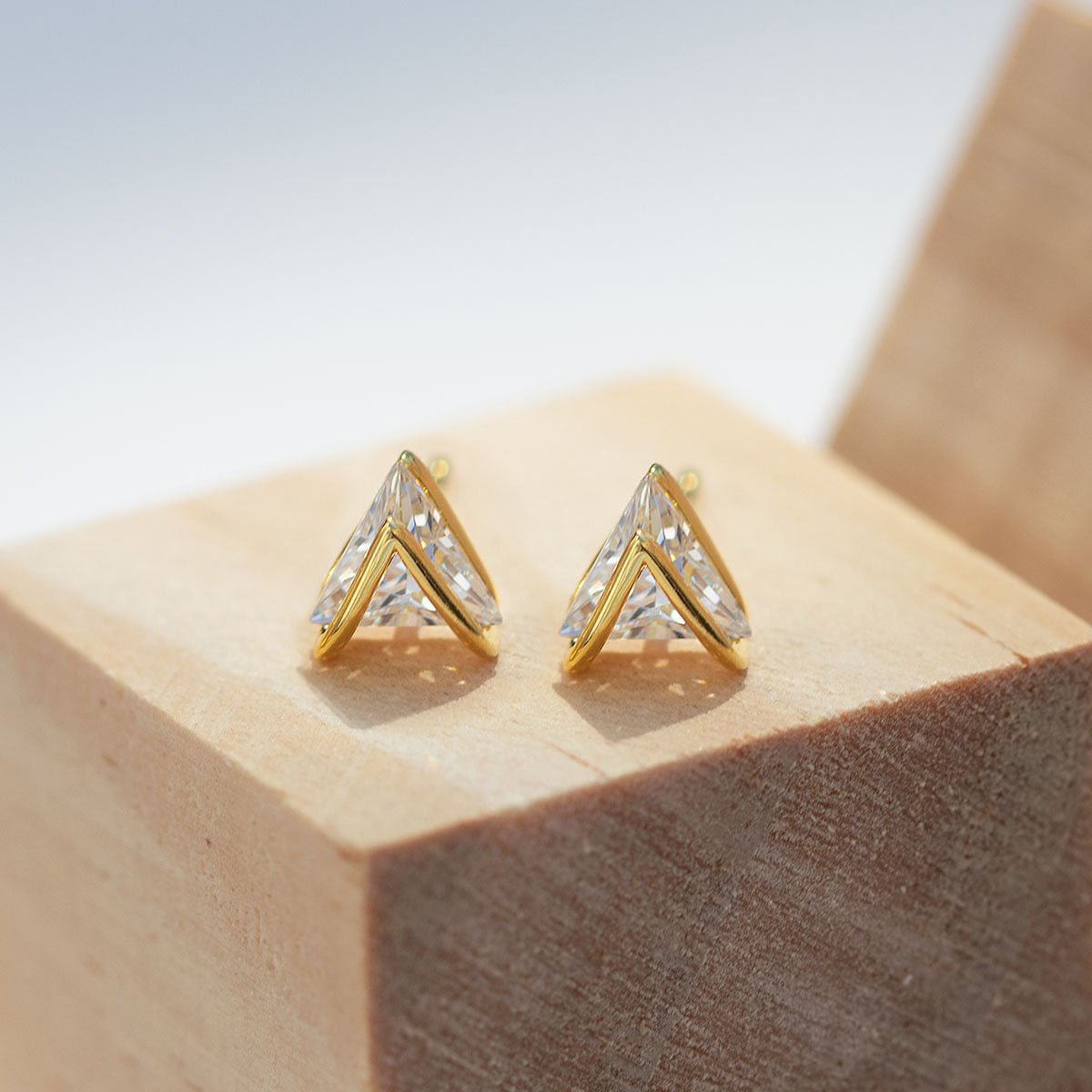 Gold vermeil chevron white zirconia studs, close-up detail resting on a wood block
