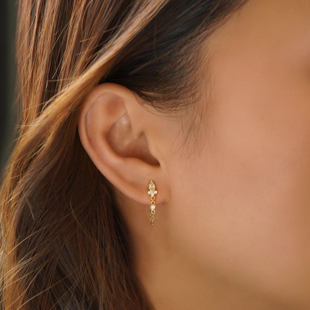 Gold vermeil chain stud earring with clear stones, draped chain shown on a model's side profile