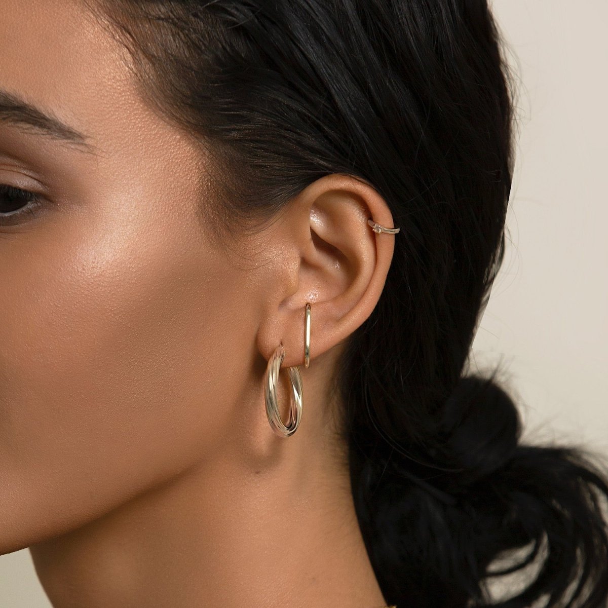 Sterling silver thin hoop earring shown on a model's lobe, with a slim ear cuff above