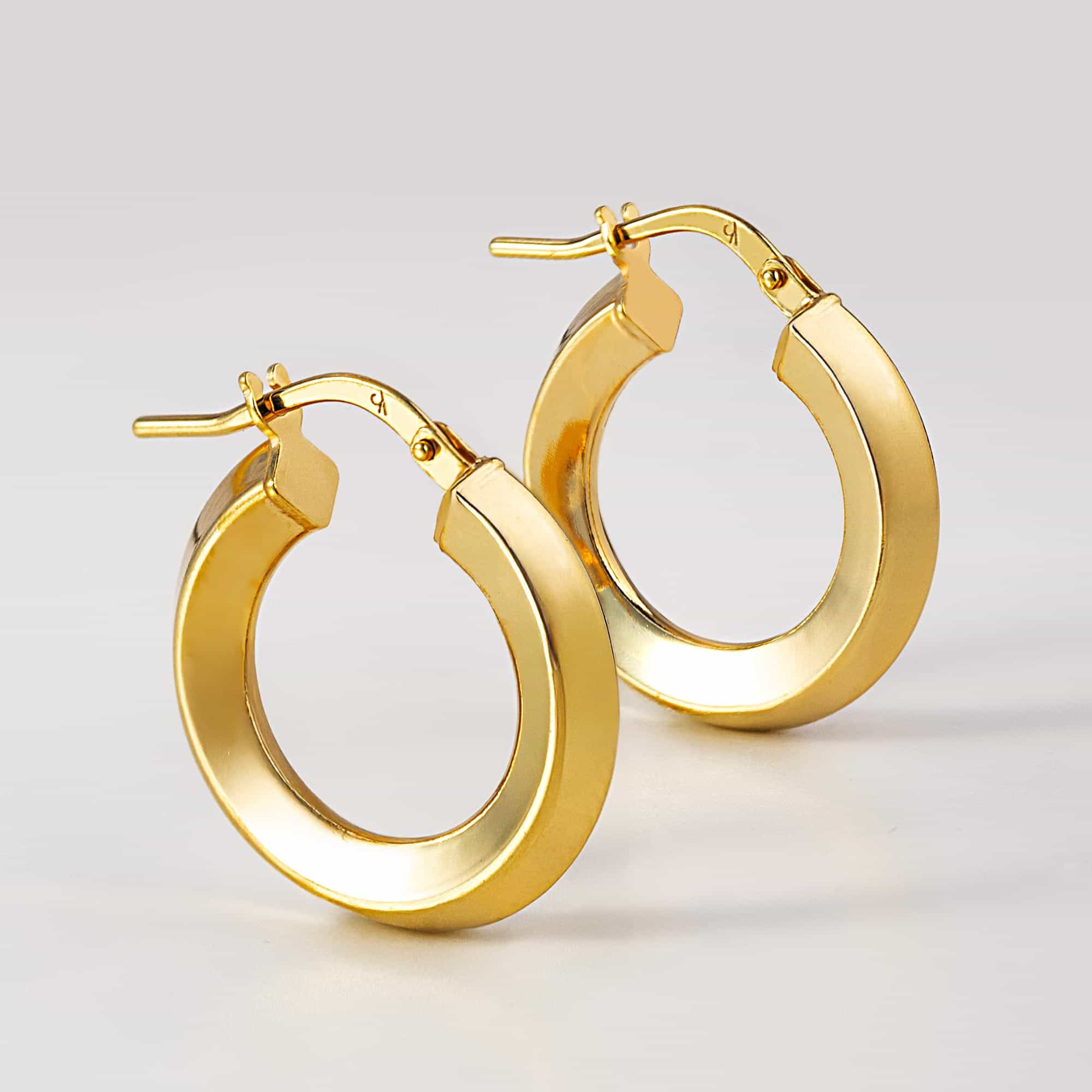 Pair of gold vermeil mini hoop earrings with a flat polished edge and hinged closure, on a white background