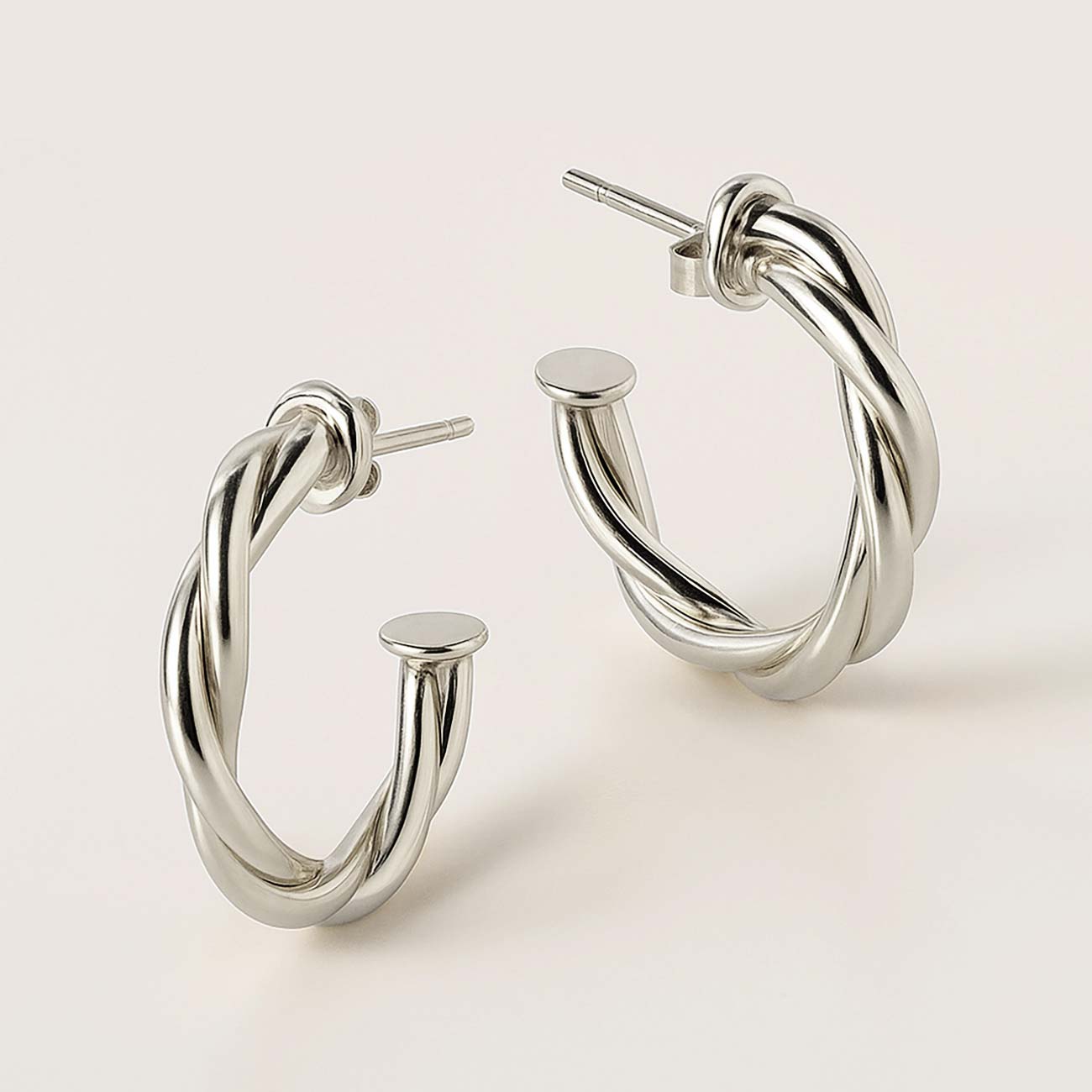 Sterling silver twisted rope C-hoop earrings, close-up detail of the open hoop and posts on a cream background