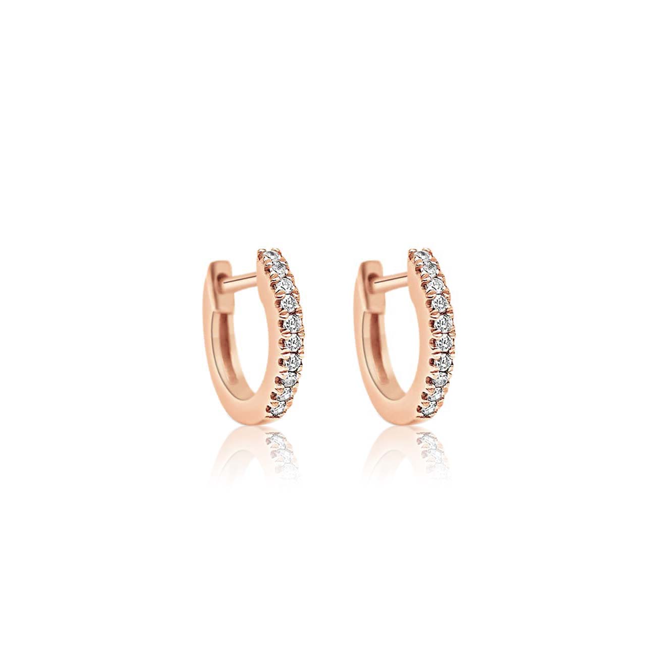 Pair of 14K rose gold pavé diamond huggie hoops with a hinged closure, on a white background
