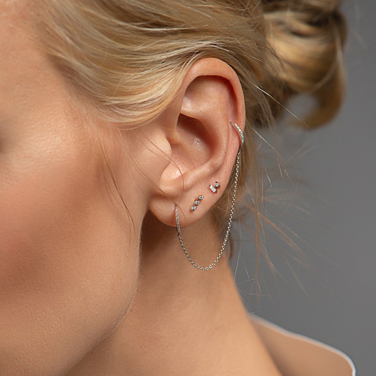 14K white gold baguette and round diamond duet studs shown stacked on a model's lobe