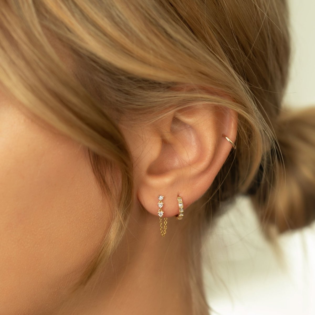 14K gold diamond drop chain stud earring shown on a model's lobe with a huggie hoop
