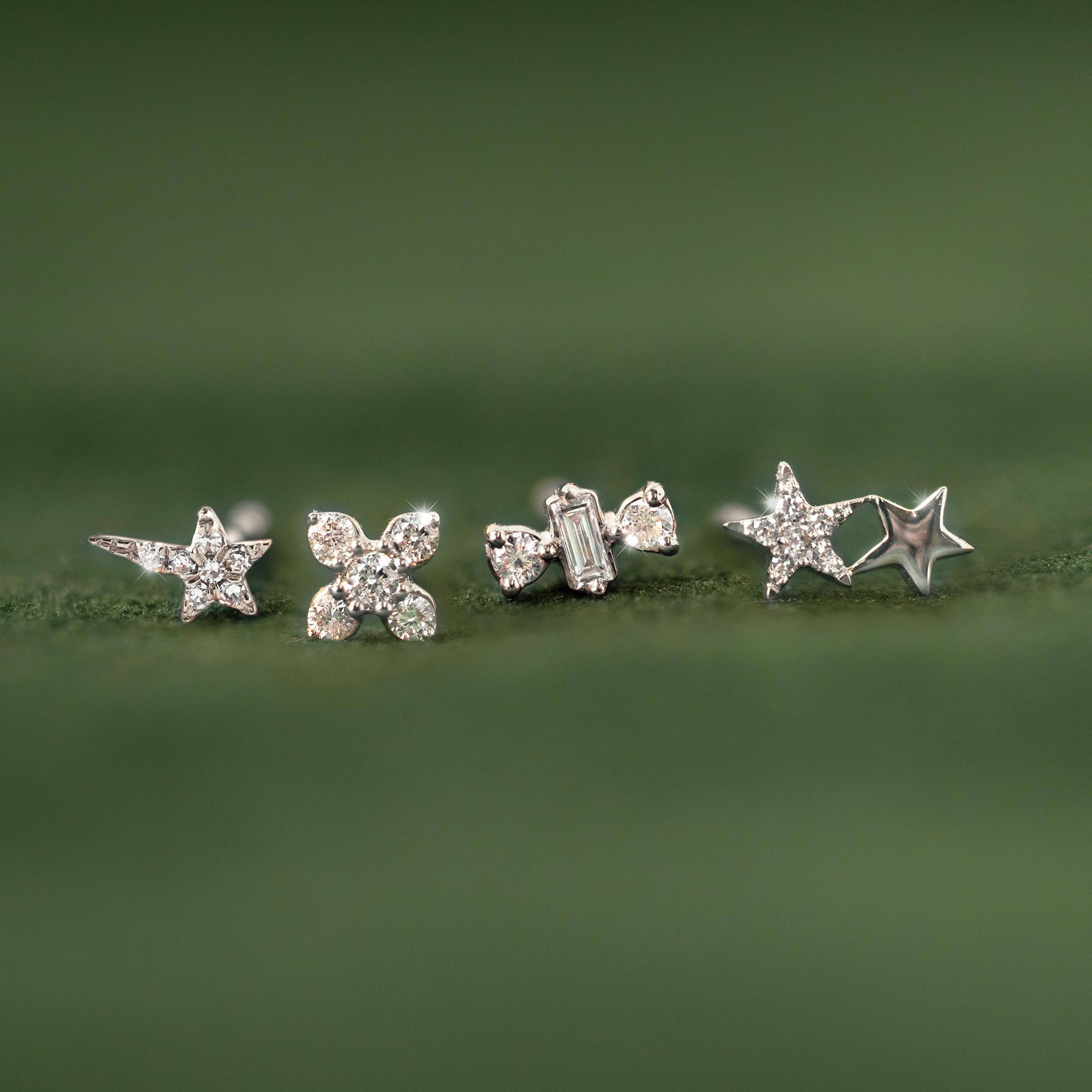 14K white gold diamond studs including the fleur design, shown in a row on a green leaf