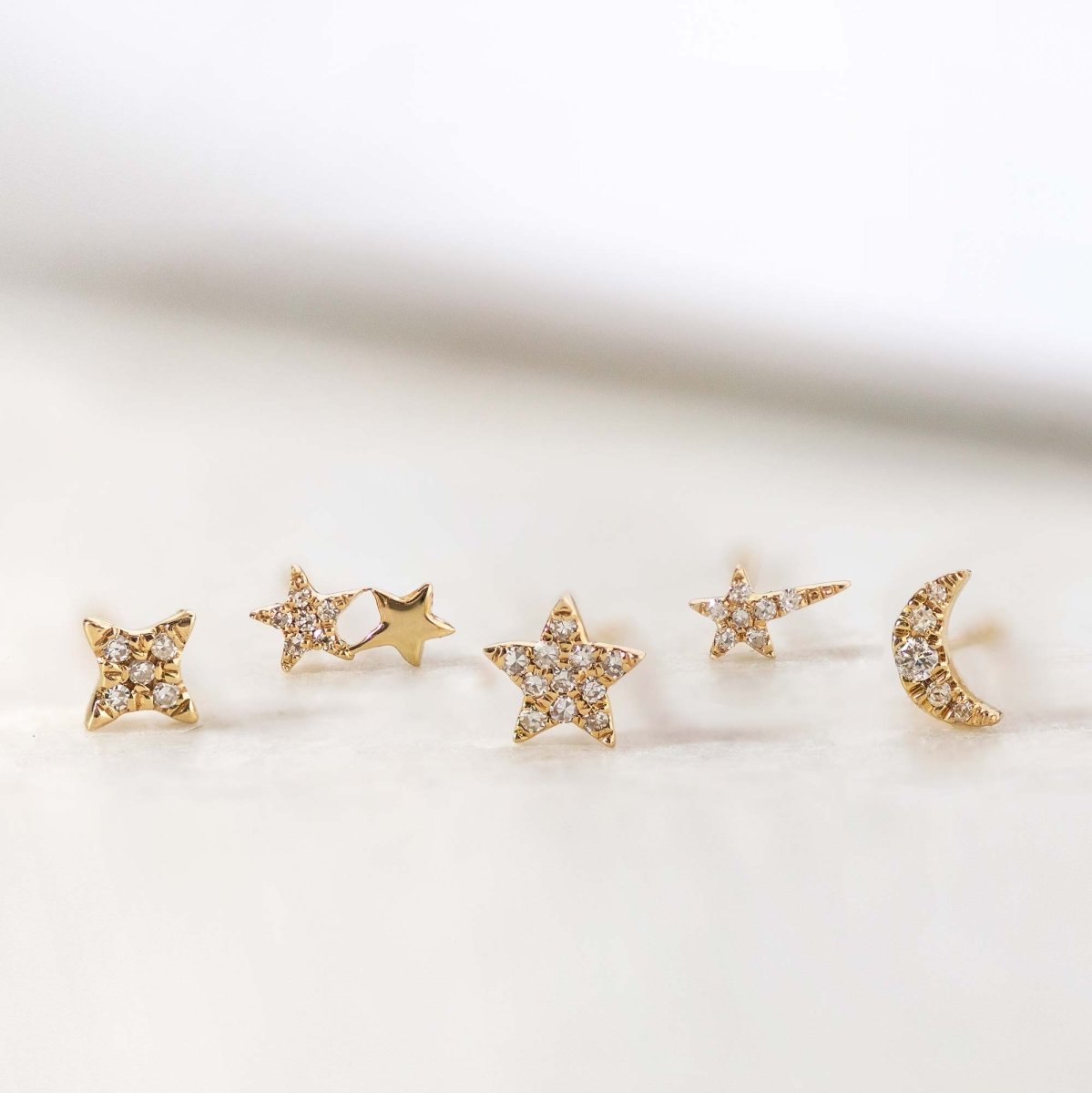 14K gold pave diamond star, four-point, moon and small star studs, on a cream background