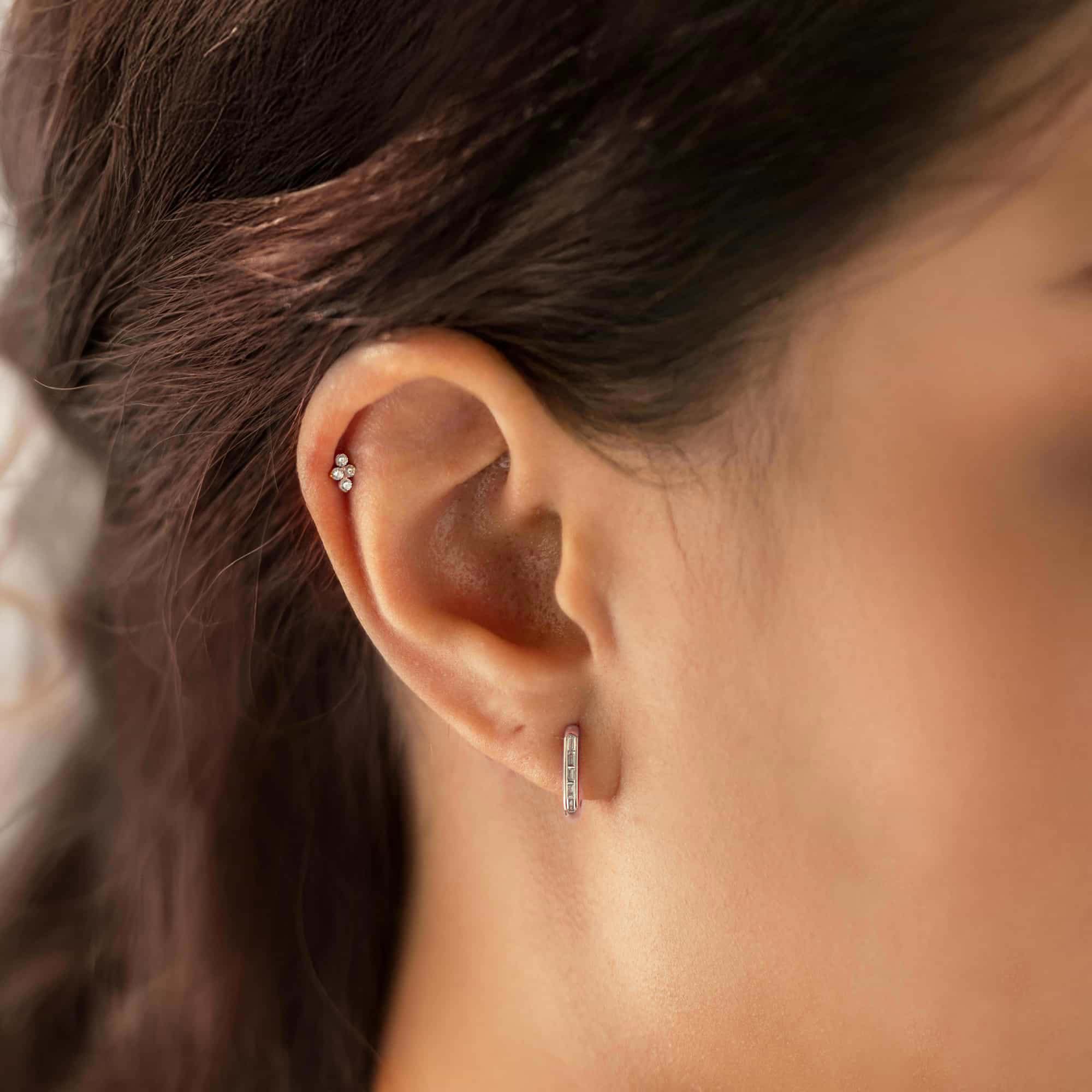 Titanium trinity flat back stud with three clear stones, shown on a model's helix