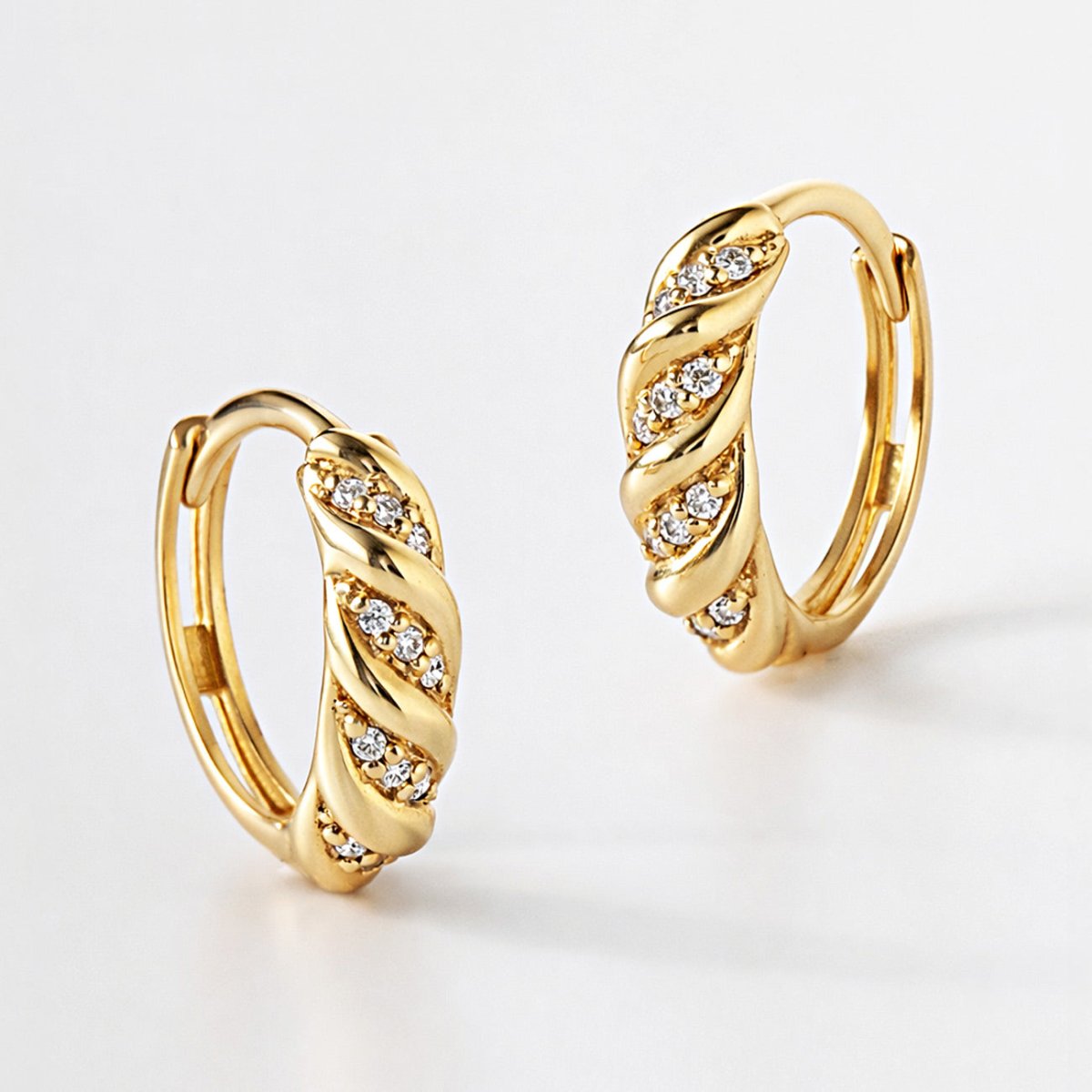 14K gold croissant huggie hoops with pave diamonds, three-quarter view on a white background