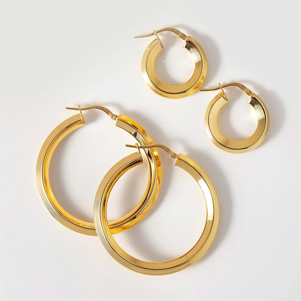 Gold vermeil flat-edge hoop earrings shown in four graduated sizes, on a white background