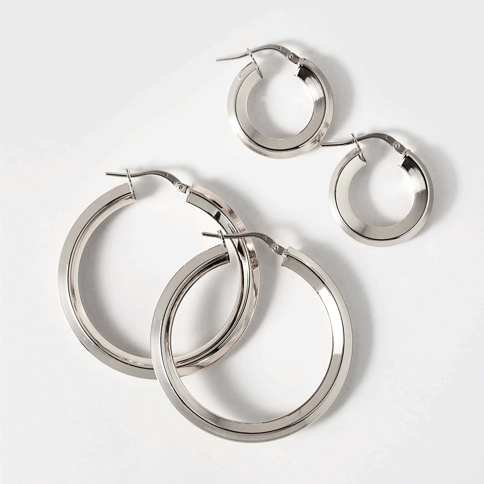 Sterling silver flat-edge hoop earrings shown in graduated sizes on a white background