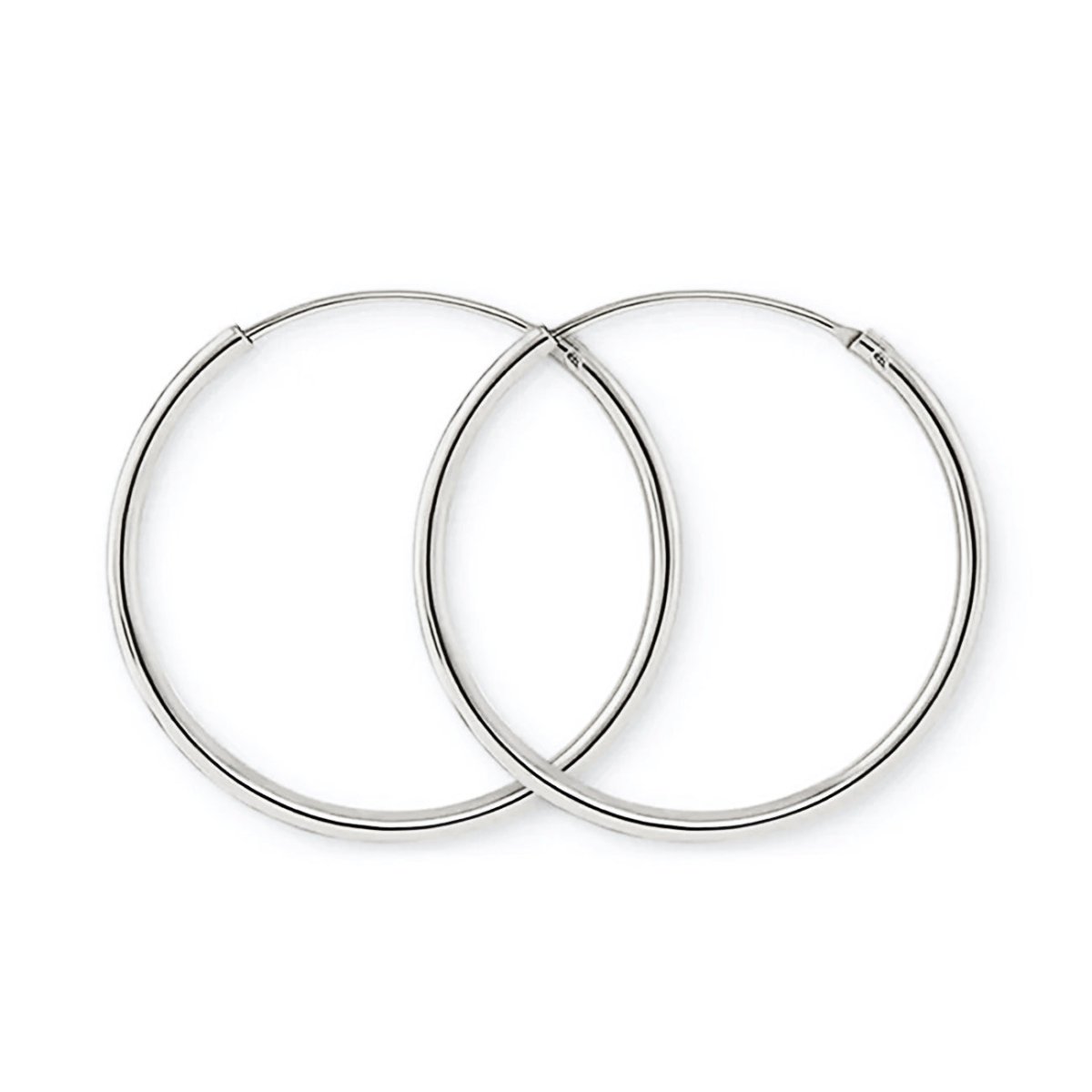 Pair of 14K white gold thin midi hoops with an endless tube closure, on a white background