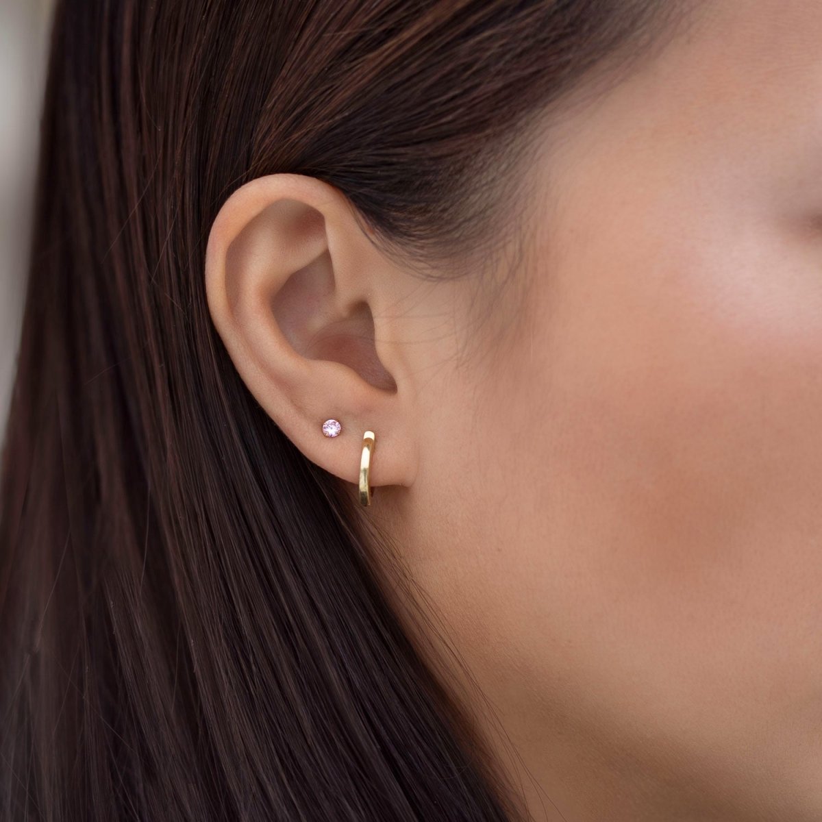 14K white gold pink sapphire tiny stud with a small round pink stone, shown on a model's lobe