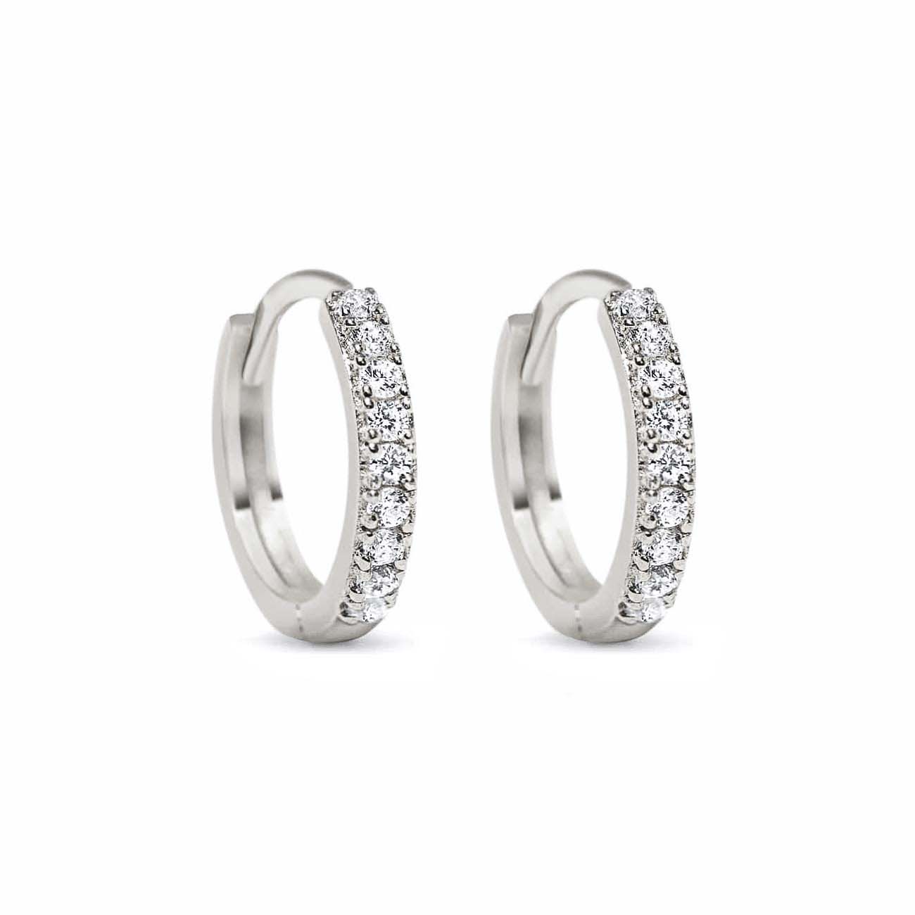 Pair of sterling silver pavé huggie hoops set with round clear stones, on a white background