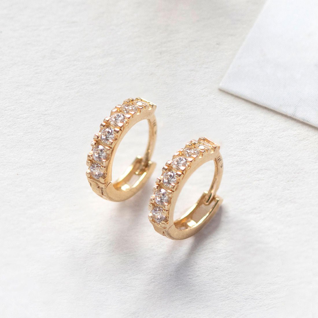 Close-up of 14k gold pave huggie earrings