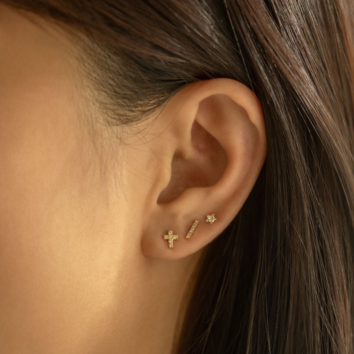 14K gold diamond bar stud shown on a model's lobe alongside other studs