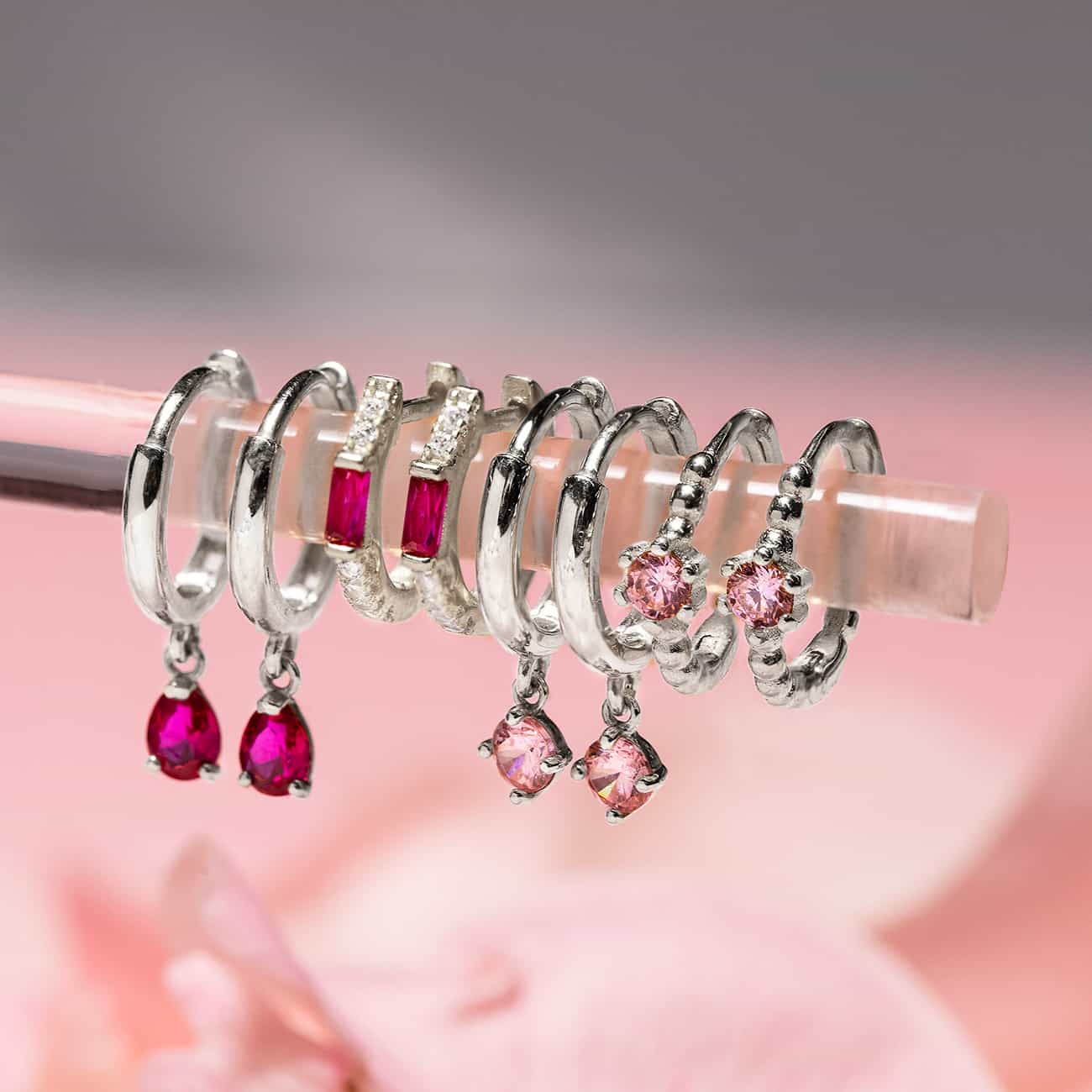 Close-up on earrings featuring Sterling Silver Gemstone Baguette Huggie Ruby + Pink Earrings.