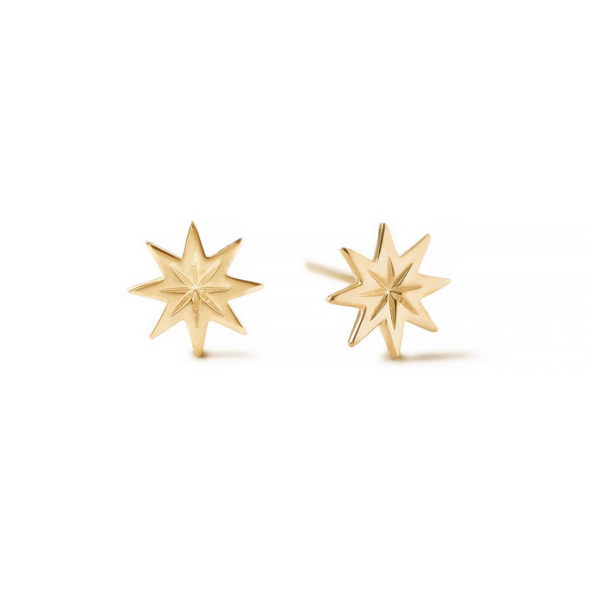 Pair of 14K gold eight-point starburst studs with an etched center, on a white background