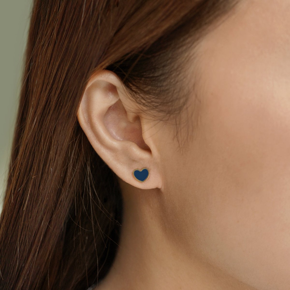14K gold heart stud with blue lapis lazuli inlay, shown on a model's earlobe