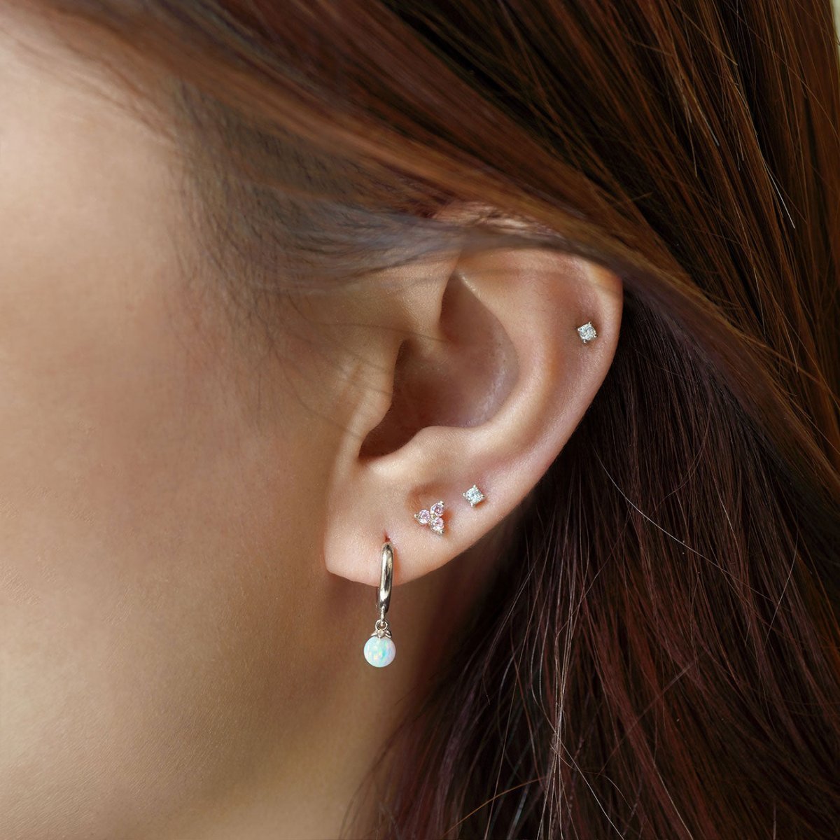 Close up of woman's ear featuring Sterling Silver Birthstone Studs Set Pink and opal hoop earring