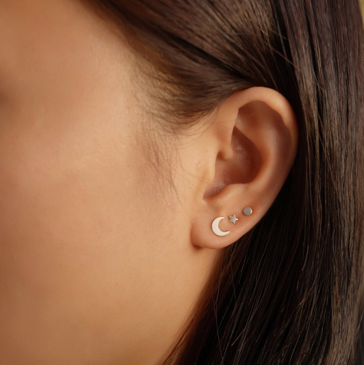 14K white gold tiny star stud shown on a model's ear, paired with a sparkle pendant stud