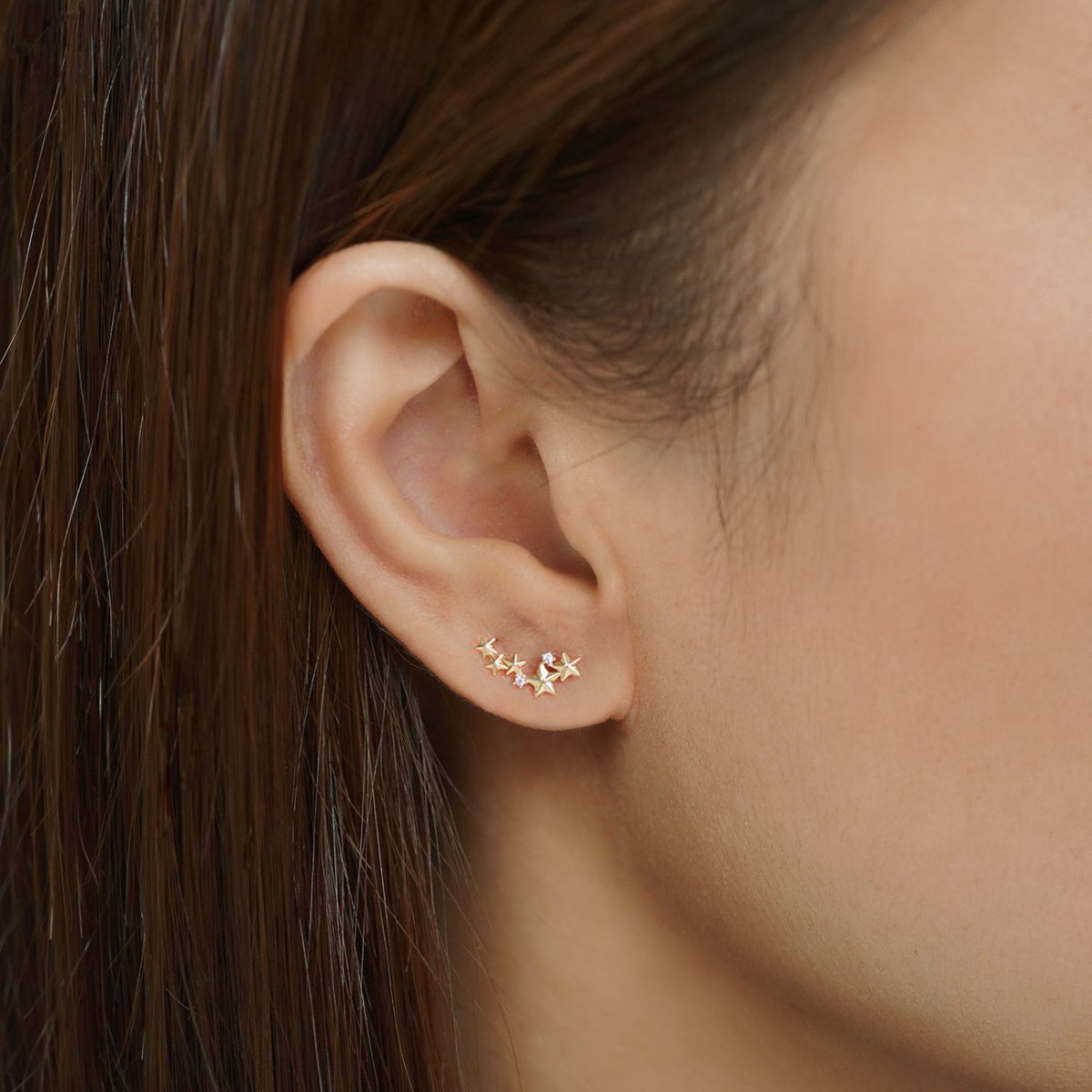 14K gold star cluster stud with clear accents shown on a model's lobe