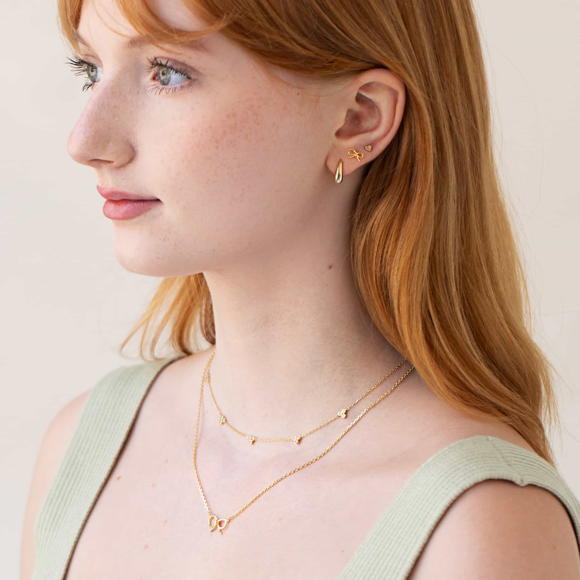 Close up of woman featuring Gold Vermeil Bow Studs and other bow gold jewelry
