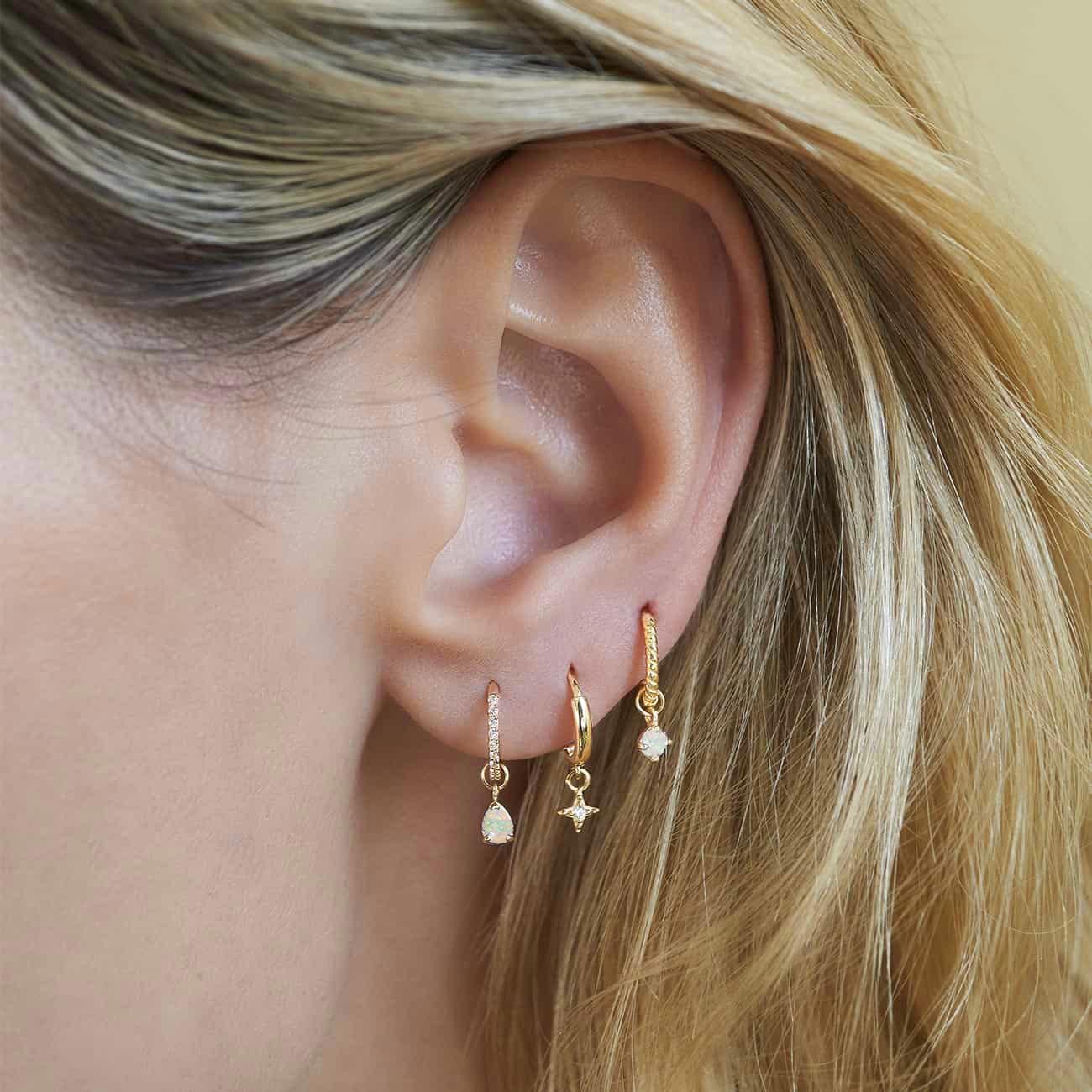 14K gold round white opal charm on a beaded huggie hoop, shown on a model's lobe